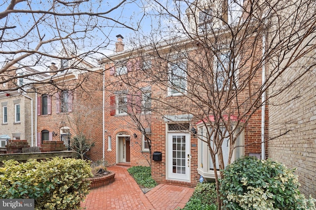 view of front of house featuring brick siding and a chimney