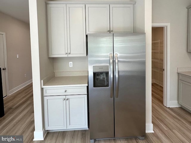 kitchen featuring light countertops, stainless steel refrigerator with ice dispenser, and light wood-style flooring