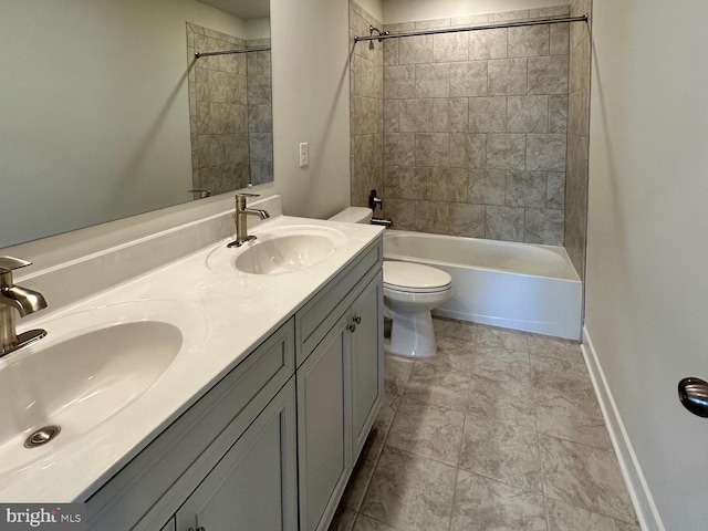 bathroom with baseboards, a sink, toilet, and double vanity