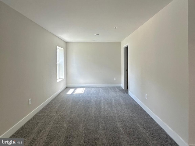 spare room featuring carpet and baseboards