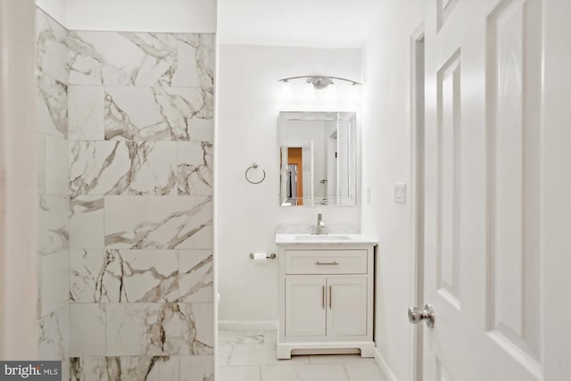 bathroom with marble finish floor, vanity, baseboards, and walk in shower