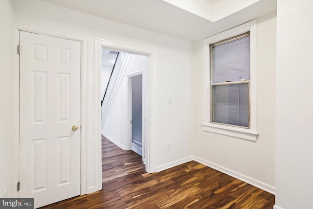 unfurnished room with baseboards and dark wood finished floors