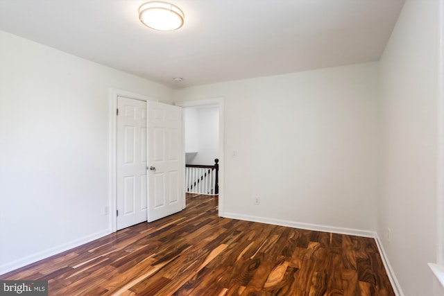 spare room with dark wood-style floors and baseboards