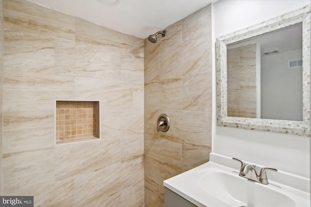 bathroom with tiled shower and vanity