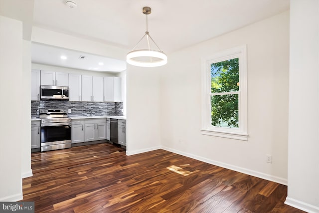 kitchen with baseboards, dark wood finished floors, decorative backsplash, stainless steel appliances, and light countertops