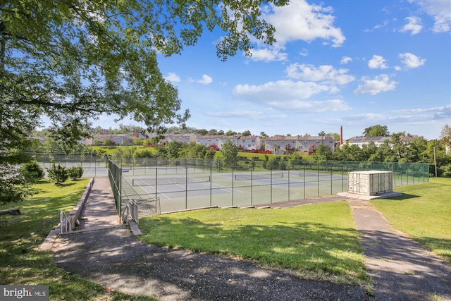 view of tennis court with fence and a yard