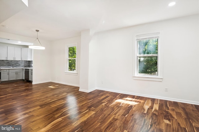 unfurnished living room with dark wood-style floors, recessed lighting, a healthy amount of sunlight, and baseboards