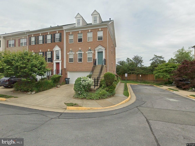 multi unit property with concrete driveway, a garage, fence, and brick siding