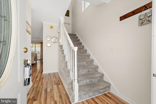 foyer with stairway, a high ceiling, light wood-style flooring, and baseboards