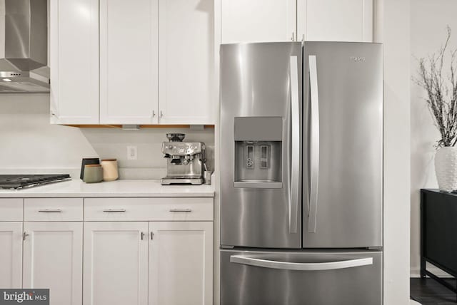 kitchen with light countertops, wall chimney range hood, white cabinets, and appliances with stainless steel finishes