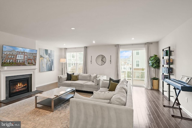 living area featuring a glass covered fireplace, dark wood-type flooring, recessed lighting, and baseboards