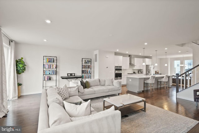 living room featuring stairway, recessed lighting, baseboards, and dark wood-style flooring