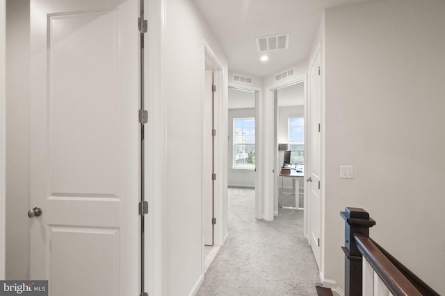 corridor featuring an upstairs landing, visible vents, and carpet