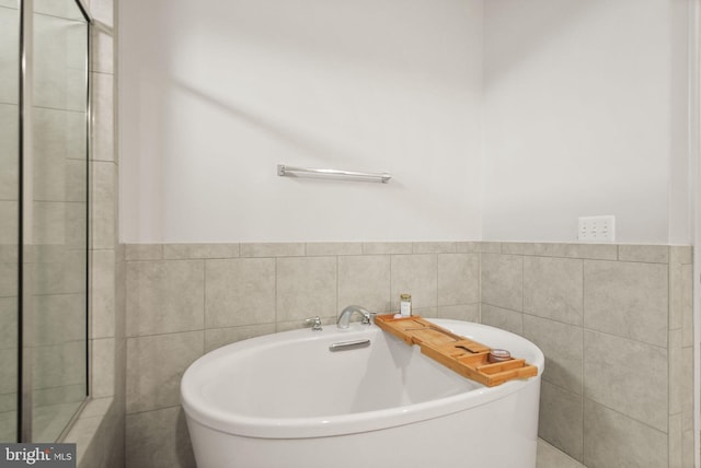 full bathroom featuring tile walls, a wainscoted wall, and a freestanding bath