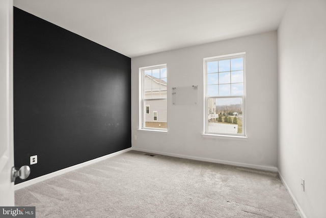 carpeted spare room with visible vents and baseboards