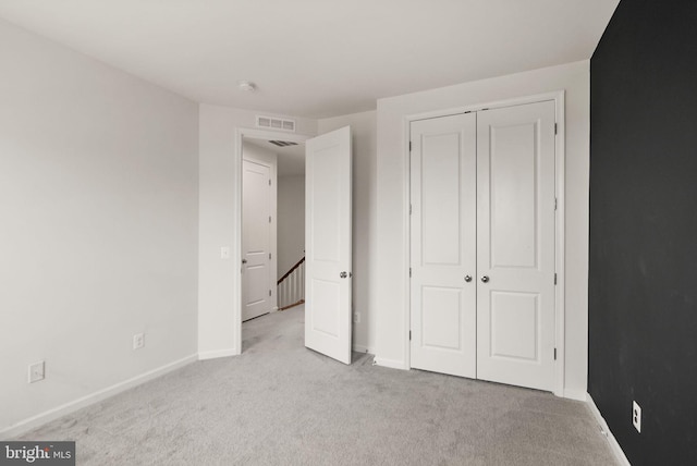 unfurnished bedroom with baseboards, carpet floors, a closet, and visible vents