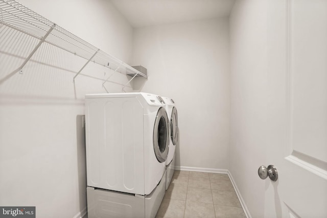 laundry room featuring laundry area, light tile patterned flooring, baseboards, and washer and clothes dryer