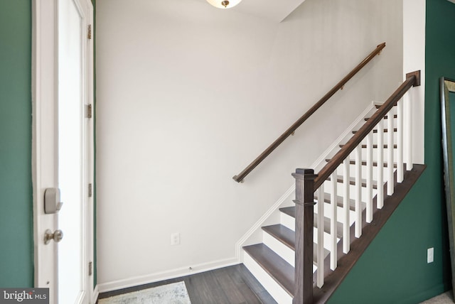 staircase featuring baseboards and wood finished floors