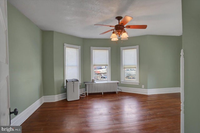 spare room with radiator, a ceiling fan, baseboards, hardwood / wood-style flooring, and a textured ceiling