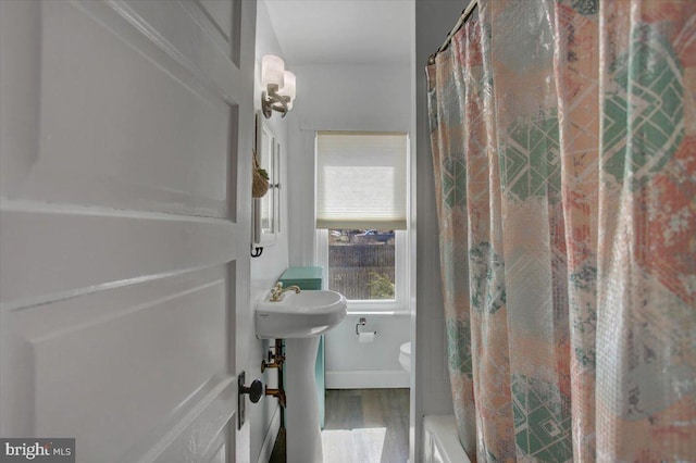 bathroom featuring a shower with shower curtain, baseboards, toilet, and wood finished floors