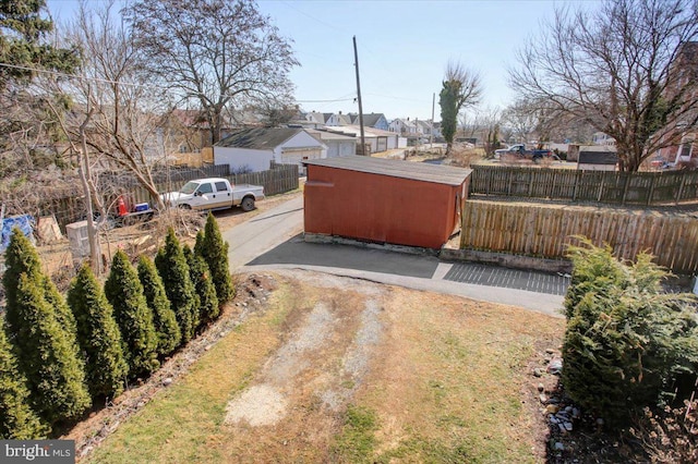 view of yard featuring a residential view, an outdoor structure, a shed, and fence