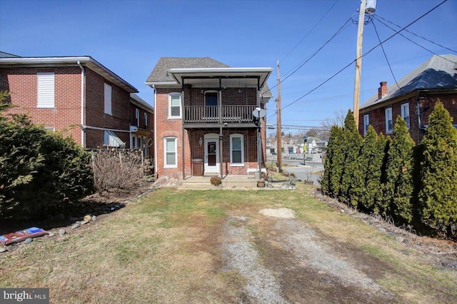 rear view of house with brick siding, a lawn, a shingled roof, and a balcony