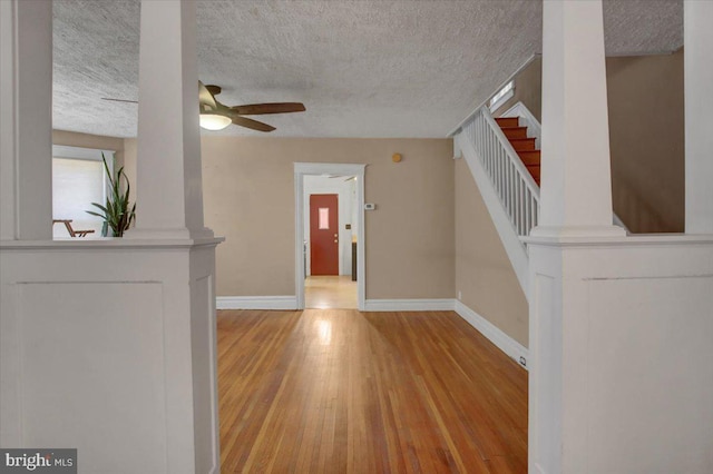 foyer featuring a textured ceiling, baseboards, light wood-type flooring, and ceiling fan