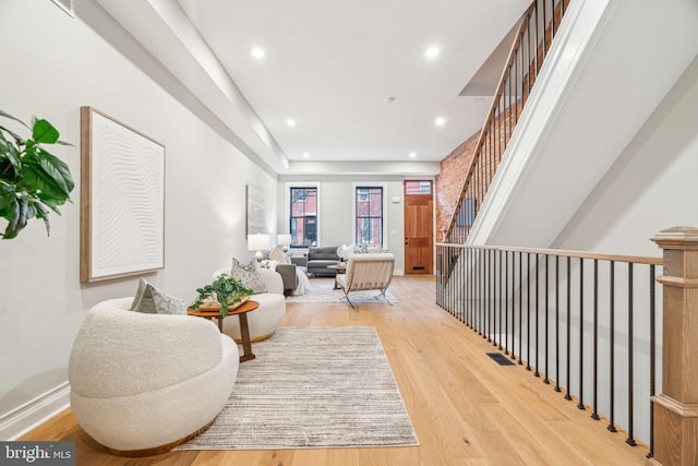 living area featuring light wood-style floors, recessed lighting, visible vents, and stairs