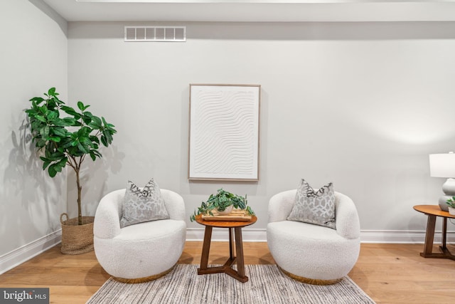 living area featuring visible vents, baseboards, and wood finished floors