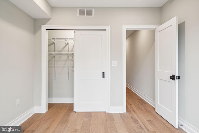 unfurnished bedroom with a closet, light wood-type flooring, visible vents, and baseboards