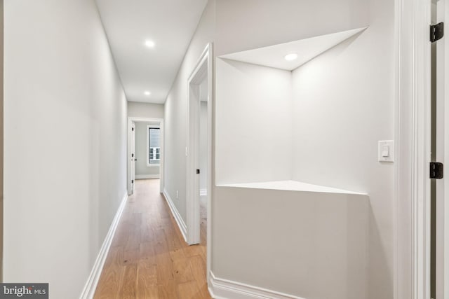 corridor with light wood-style flooring, baseboards, and recessed lighting