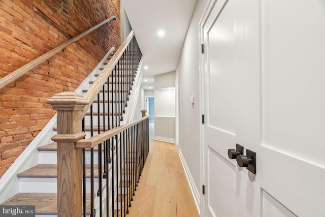 interior space featuring brick wall, recessed lighting, wood finished floors, and baseboards