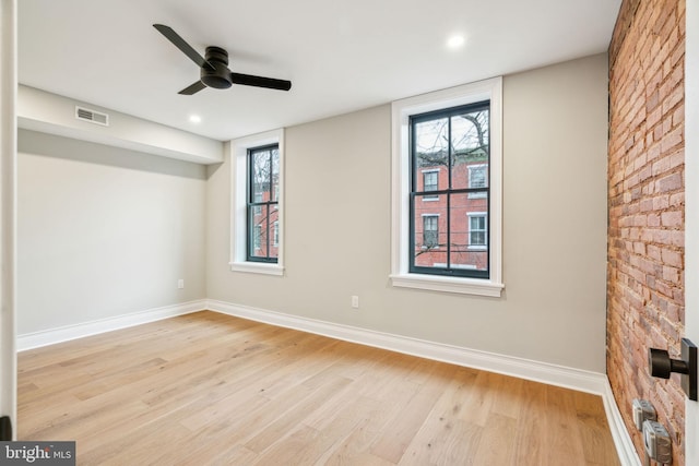 unfurnished room with light wood finished floors, a ceiling fan, visible vents, and baseboards