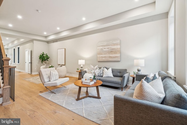 living room featuring light wood-type flooring, visible vents, recessed lighting, and stairs