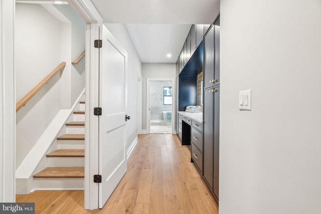 hall with light wood-type flooring and stairway