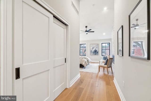 corridor with baseboards, visible vents, and light wood finished floors