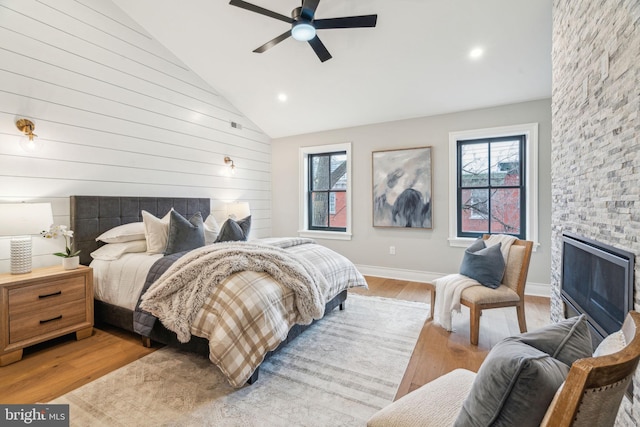 bedroom featuring multiple windows, a fireplace, and light wood-style flooring