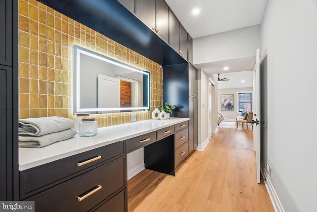 interior space featuring baseboards, wood finished floors, vanity, backsplash, and recessed lighting