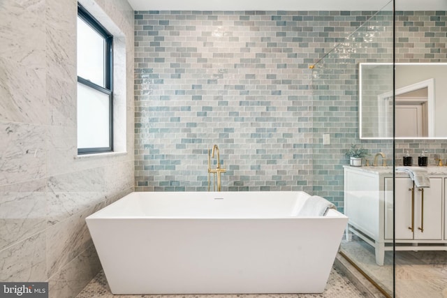 bathroom featuring a freestanding bath, tile walls, and vanity