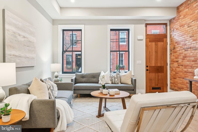 living area featuring brick wall and wood finished floors