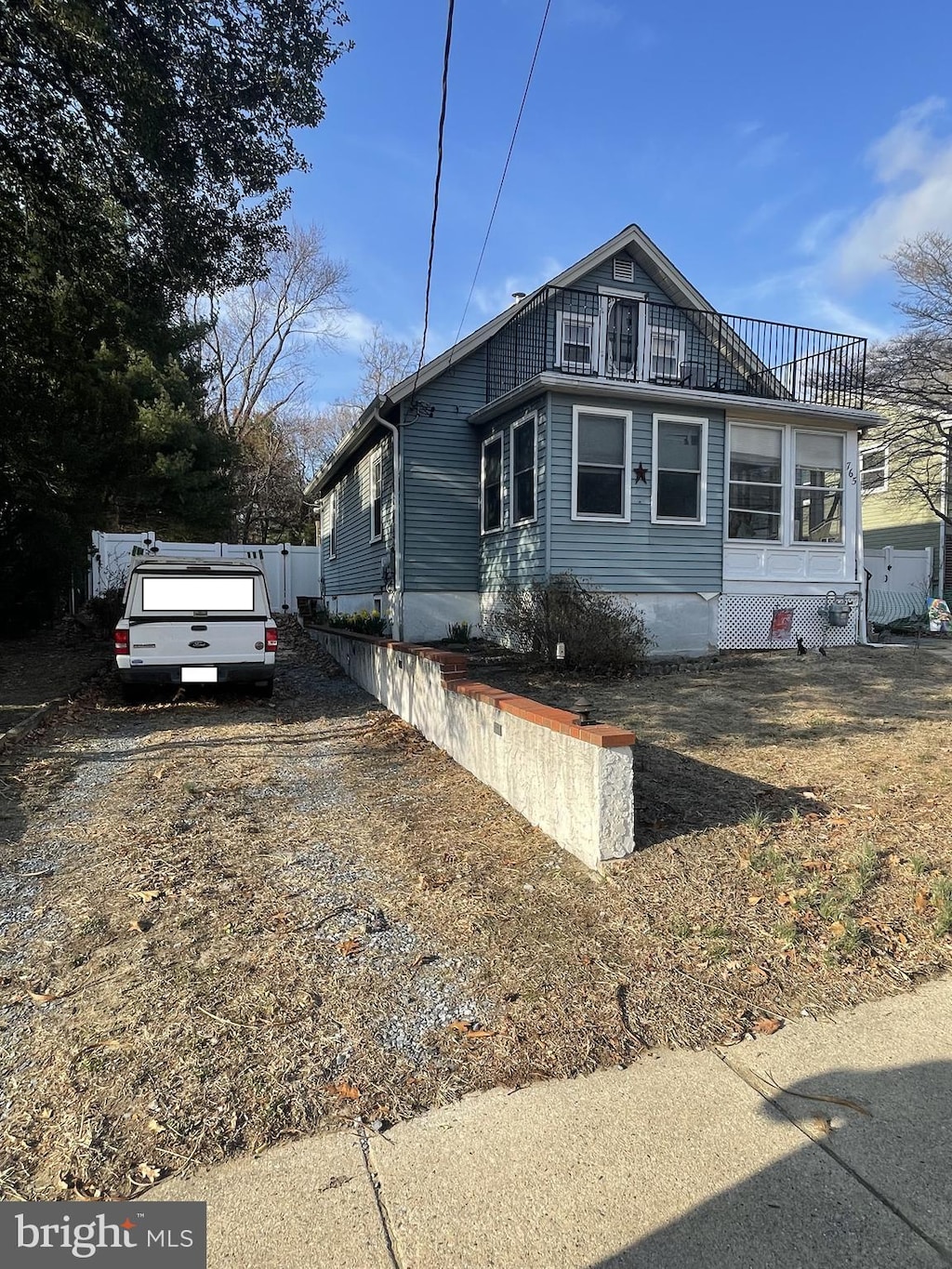 view of side of property featuring driveway, a balcony, and fence