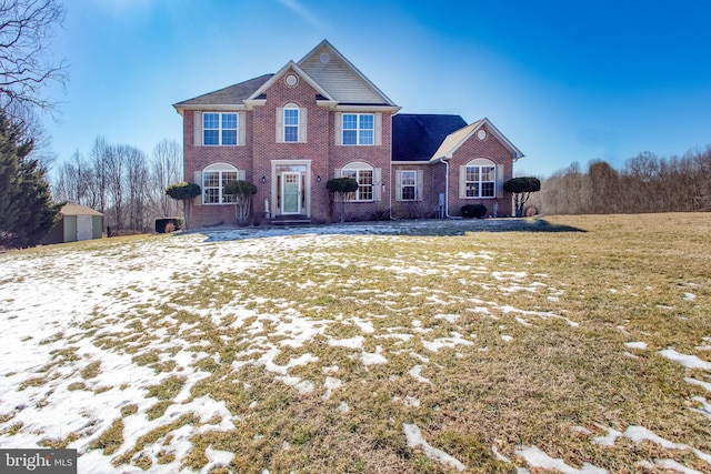 view of front of house featuring a storage shed, brick siding, a front lawn, and an outdoor structure