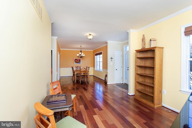 interior space with visible vents, baseboards, wood finished floors, an inviting chandelier, and crown molding