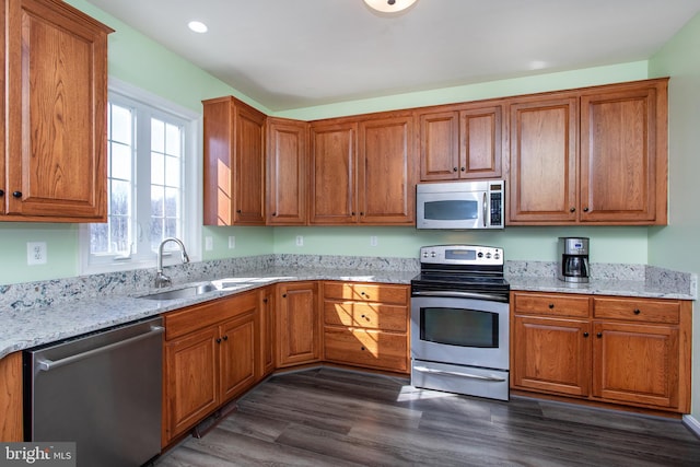 kitchen featuring appliances with stainless steel finishes, brown cabinetry, and a sink