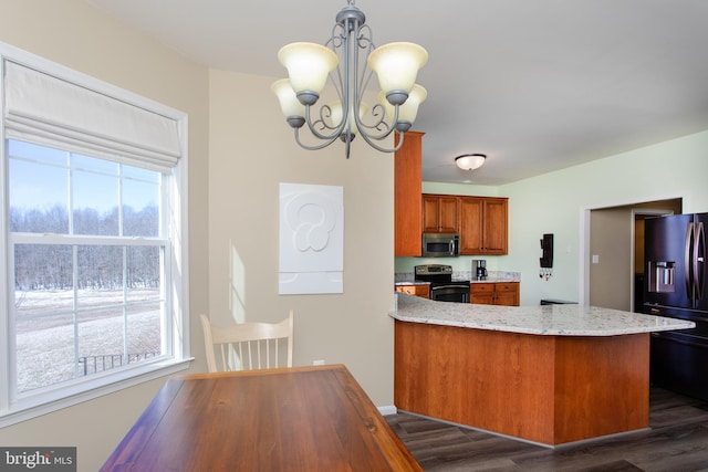 kitchen featuring dark wood-style flooring, a notable chandelier, stainless steel appliances, brown cabinetry, and a peninsula