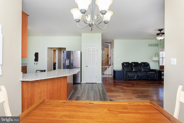 kitchen featuring stainless steel fridge, visible vents, wood finished floors, a peninsula, and ceiling fan with notable chandelier