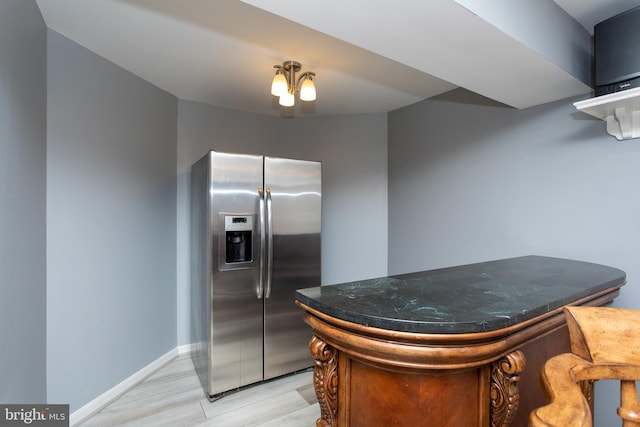 kitchen featuring stainless steel fridge, baseboards, and dark stone counters