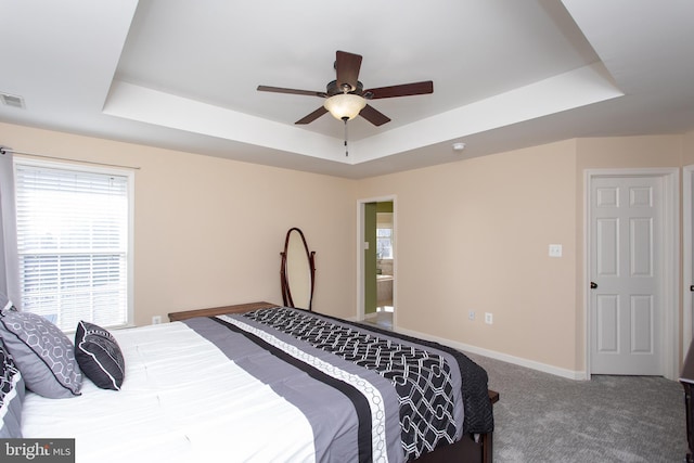 bedroom with carpet, baseboards, a raised ceiling, and a ceiling fan