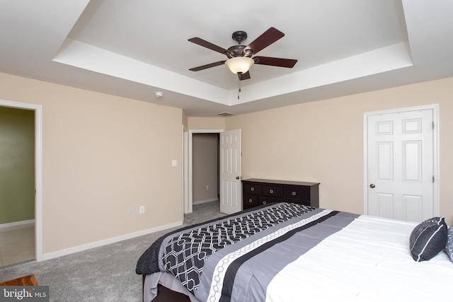 bedroom featuring carpet floors, a raised ceiling, a ceiling fan, and baseboards