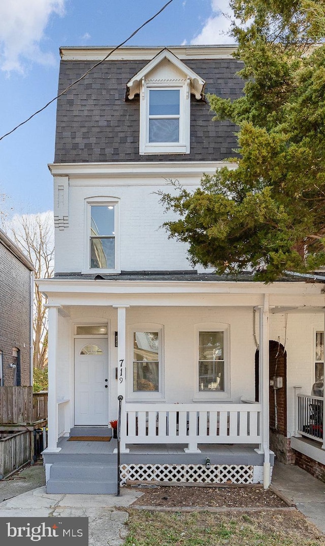 view of front of home featuring a porch, a shingled roof, and fence